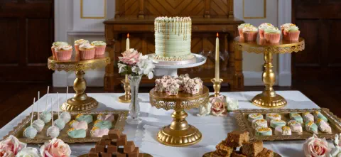 A lavish wedding dessert table adorned with popsicles, fudge, cupcakes, treats, macarons and more